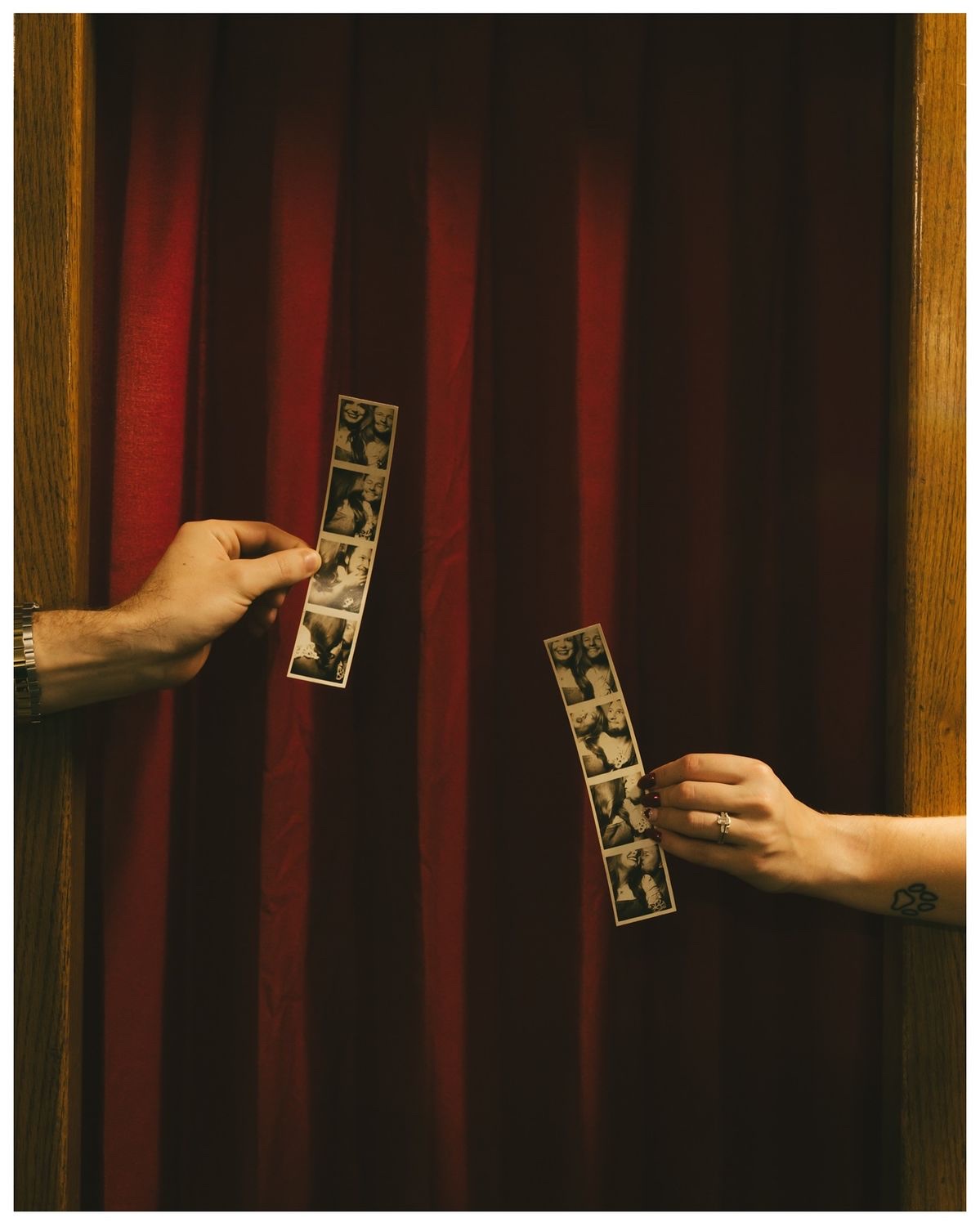 Guests exchanging printed photo strips in front of a red curtain